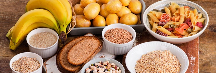 carbohidratos complejos y simples frutas legumbres semillas y pan sobre mesa de madera