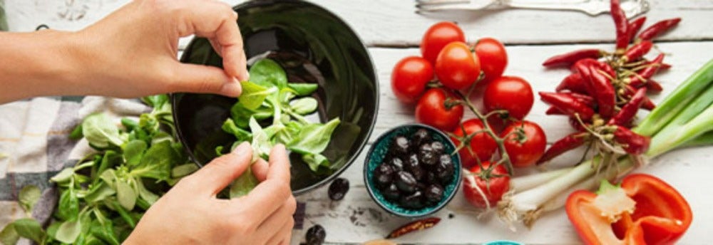 Preparación de ensalada con tomate, pimentón y espinacas, que son alimentos con vitamina A