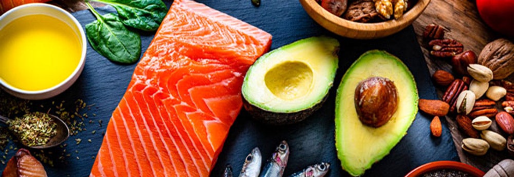 Alimentos fuente de grasas saludables, como aguacate, salmón y frutos secos.