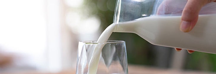 Persona sirve un vaso de leche, un alimento con nutrientes esenciales