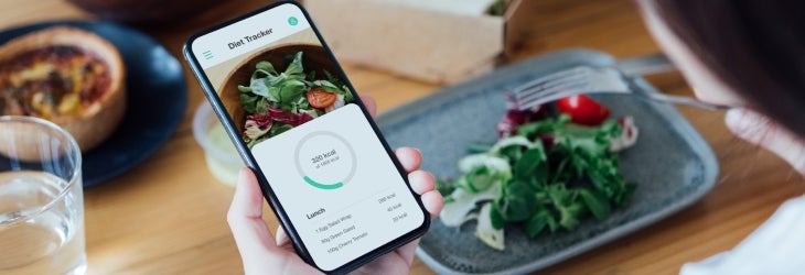 Mujer utiliza su smartphone para calcular las calorías que come y aplicar un déficit calórico