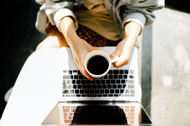 Manos con una taza de café NESCAFÉ® mostrando un computador