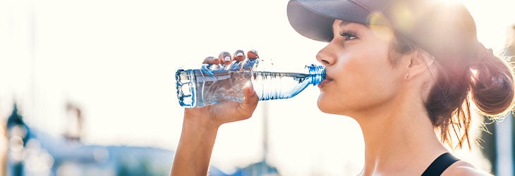 Mujer bebe agua para recuperar y tener más energía luego de entrenar