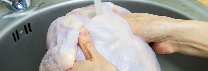 Mujer lava pollo crudo y fresco para luego deshuesarlo 