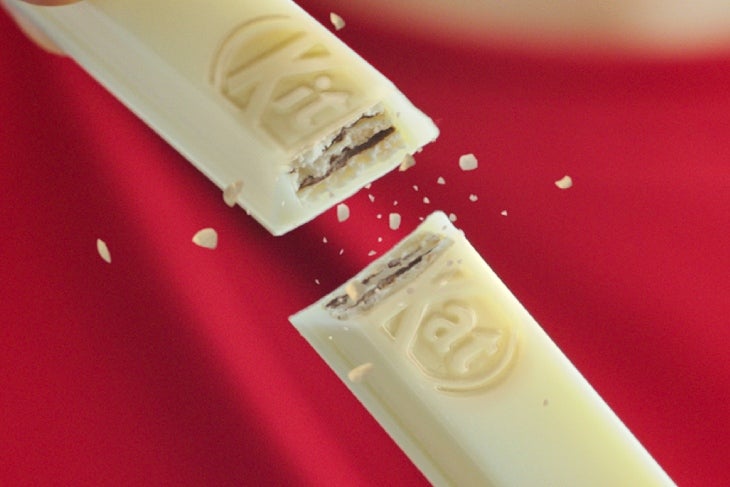 Manos rompiendo una galleta de KITKAT®