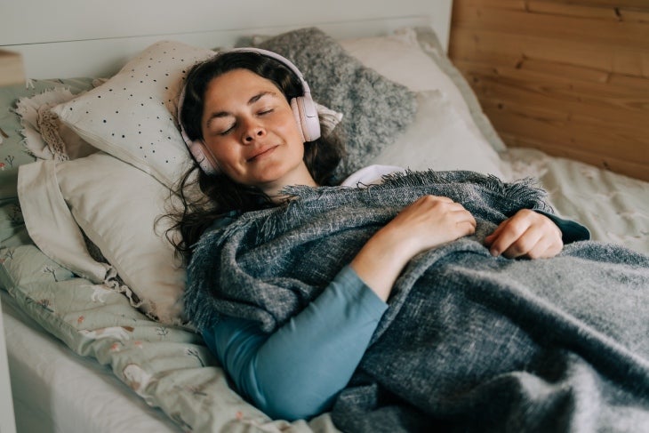 Tips efectivos para aplicar la higiene del sueño correctamente Mujer escuchando música relajante antes de dormir