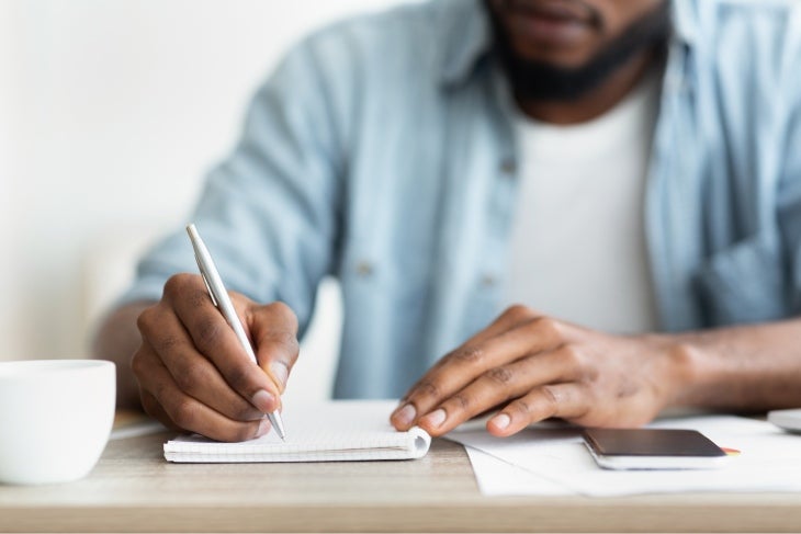 Hombre escribiendo en un cuaderno su resumen del día