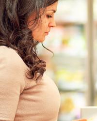 mujer en supermercado leyendo tabla nutricional de un alimento