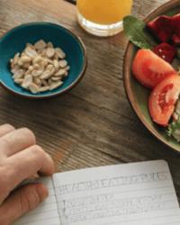 Persona haciendo un listado de alimentos saludables y porciones adecuadas