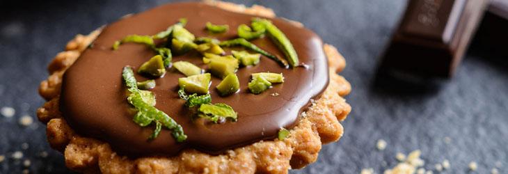 Receta dulce como la tartaleta de chocolate oscuro, pistachos y ralladura de lima