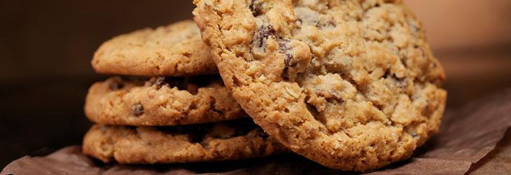 Cuatro galletas integrales caseras hechas de avena y chips de chocolate sobre una tabla