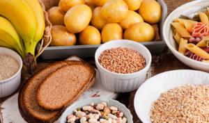 carbohidratos complejos y simples frutas legumbres semillas y pan sobre mesa de madera