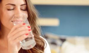 Mujer disfruta tomar agua en casa por sus diversos beneficios para la salud