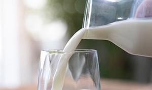 Persona sirve un vaso de leche, un alimento con nutrientes esenciales